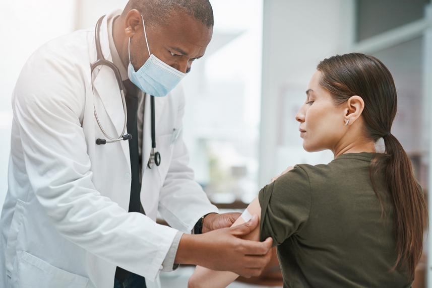 Doctor putting a bandaid on a women who just got a shot