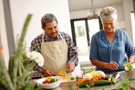 A couple in the kitchen cutting up vegetables